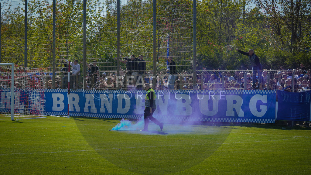 Fußball, Herren, Saison 2025/2026, Brandenburgliga, 23. Spieltag, Brandenburger SC Süd 05 vs. BSG Stahl Brandenburg, Samstag 25.04.2026, Werner-Seelenbinder-Sportplatz Brandenburg an der Havel | Fußball, Herren, Saison 2025/2026, Brandenburgliga, 23. Spieltag, Brandenburger SC Süd 05 vs. BSG Stahl Brandenburg, Samstag 25.04.2026, Werner-Seelenbinder-Sportplatz Brandenburg an der Havel, Im Bild: Ein Pyro Körper wurde auf das Spielfeld geworfen und wird von einer Sicherheitskraft entfernt - Realisiert mit Pictrs.com