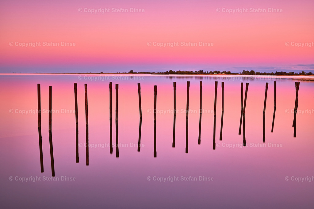 pink sky reflection in the water with stakes in the water | pink sky reflection in the water with stakes in the water - Realisiert mit Pictrs.com