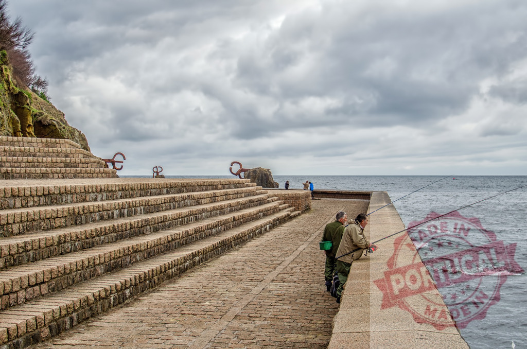 Fishermen casting rods by El Peine del Viento in San Sebastián | Men fishing from a seawall with Comb of the Wind sculptures and a cloudy sky - Realisiert mit Pictrs.com
