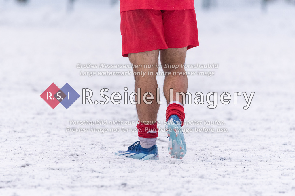 RS-1-024557 | Fußballer mit heruntergeschobenen roten Stutzen und blauen Stollenschuhen im Schnee.