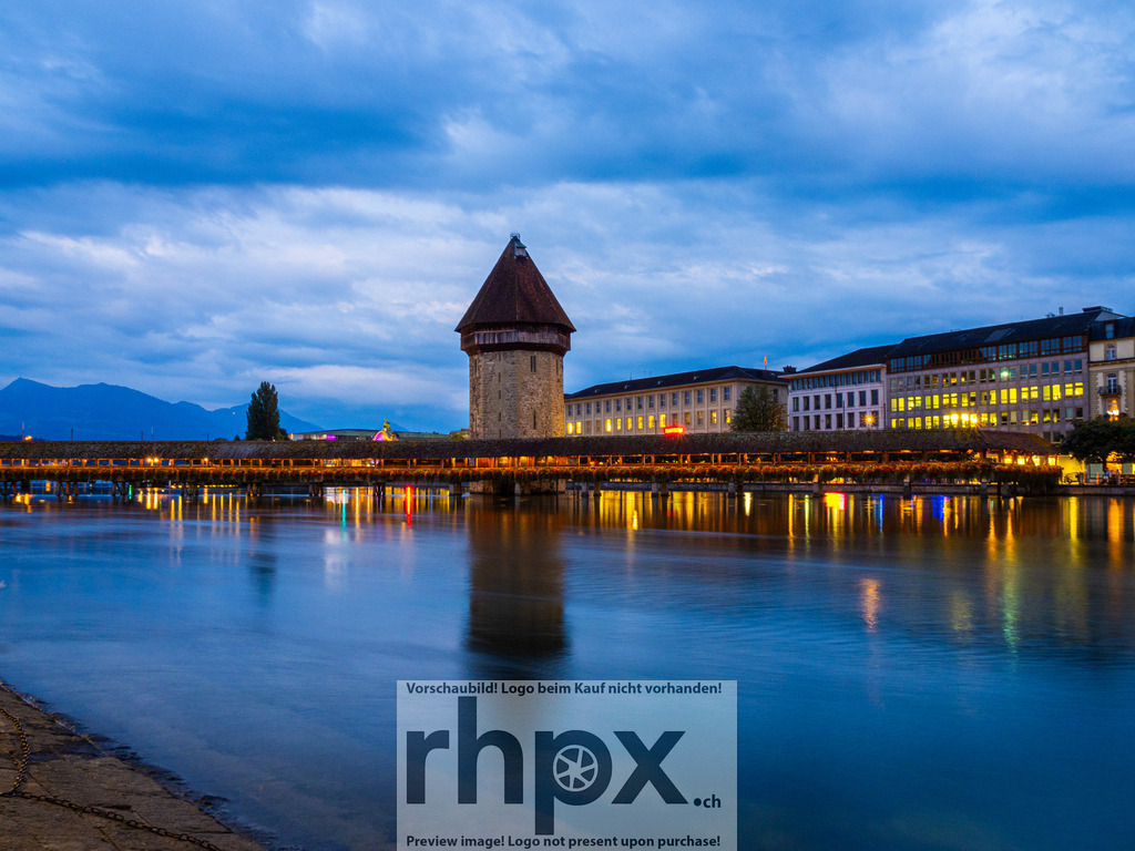 Kapellbrücke | Architektur. Stille. Eleganz.Die Kapellbrücke und der markante Wasserturm spiegeln sich sanft im ruhigen Wasser der Reuss, während der Pilatus im Hintergrund über der Stadt wacht. Ein stimmungsvoller Moment in der blauen Stunde, der die zeitlose Schönheit Luzerns einfängt.Wähle unter "Produktauswahl" dein Wunschformat: Vom klassischen Wandbild über Puzzle &amp; Tassen bis zum digitalen Download (z.B. als Handy-Hintergrund). - Realisiert mit Pictrs.com