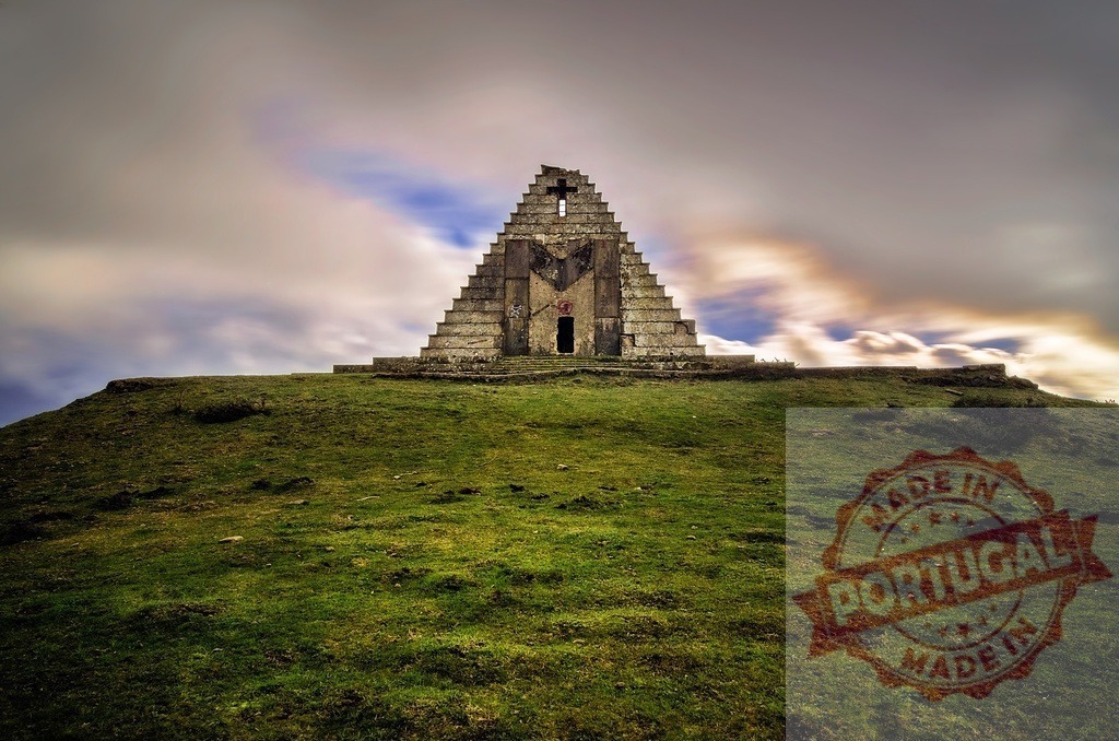 Ancient pyramid monument on green hill with clouds | Stone pyramid structure standing on a grassy hill under streaking clouds - Realized with Pictrs.com