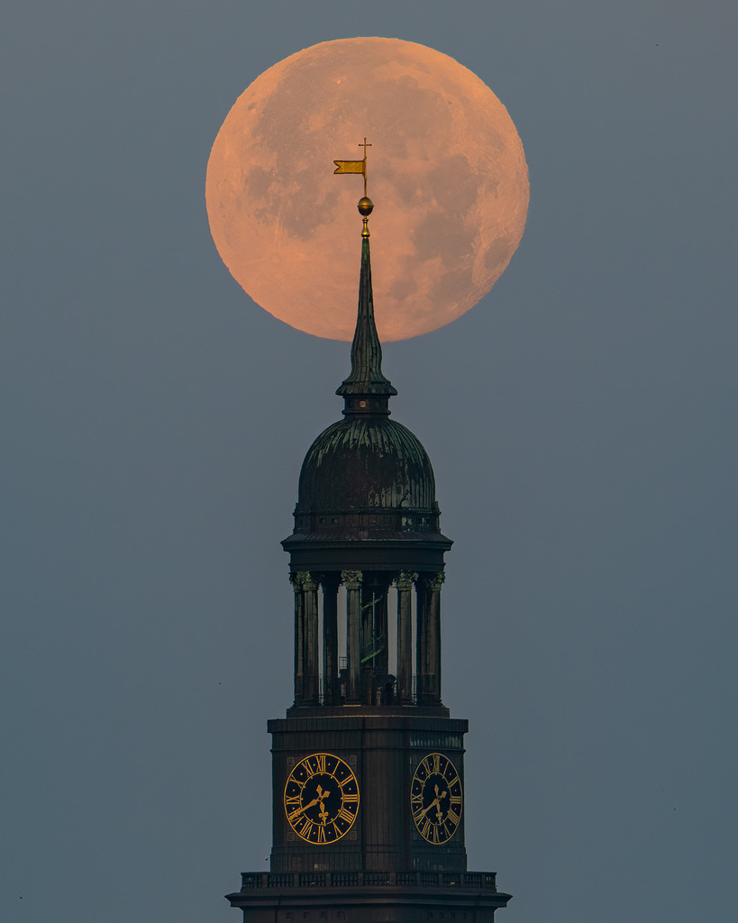 Vollmond über der Turmspitze des Hamburger Michel | Teleaufnahme des Hamburger Michel mit großem Vollmond direkt über der Turmspitze in der morgendlichen Dämmerung. - Realisiert mit Pictrs.com