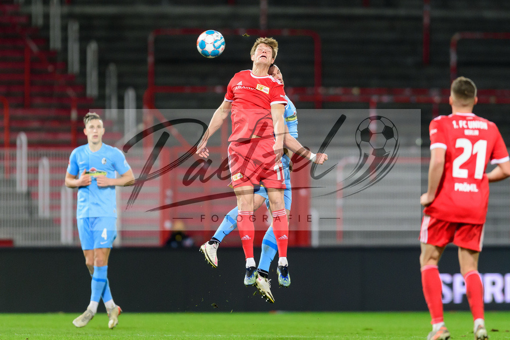 FCUFRE20211215_053 | Fussball, Herren: Kevin Behrens (1. FC Union Berlin) und Nicolas Hoefler (SC Freiburg) im Zweikampf bei dem Spiel der 1. Bundesliga zwischen 1. FC Union Berlin und SC Freiburg im Stadion An der Alten Foersterei am 15.12.2021 in Berlin, Deutschland.DFB / DFL REGULATIONS PROHIBIT ANY USE OF PHOTOGRAPHS AS IMAGE SEQUENCES AND/OR QUASI-VIDEO. - Realisiert mit Pictrs.com