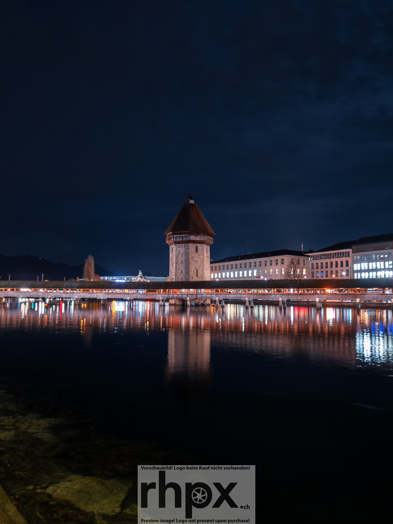 Nächtliche Ansicht von Luzern | Wasser. Licht. Historie.Die Kapellbrucke in Luzern, eingefangen in der tiefen, blauen Stunde. Die warmen Lichter der Altstadt spiegeln sich im ruhigen Wasser der Reuss und tauchen den Wasserturm in eine mystische Atmosphare.Wähle unter "Produktauswahl" dein Wunschformat: Vom klassischen Wandbild über Puzzle &amp; Tassen bis zum digitalen Download (z.B. als Handy-Hintergrund). - Realisiert mit Pictrs.com
