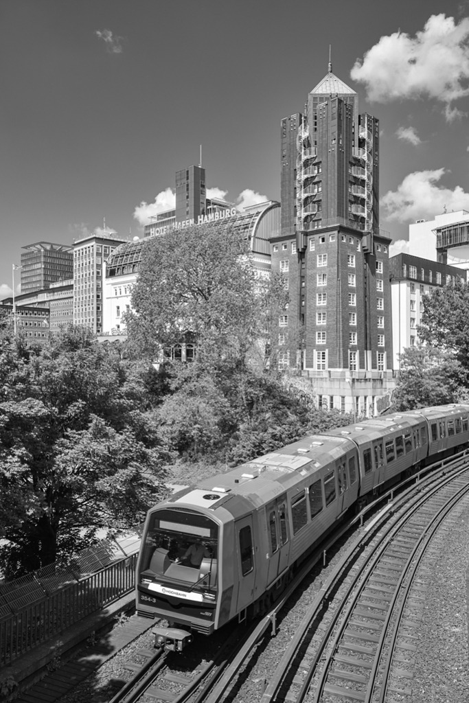 U3 in Hamburg | Die U-Bahn der Linie 3 kurz vor der Einfahrt in die Station Landungsbrücken in Hamburg. Im Hintergrund sind Häuser zu sehen, von denen aus man einen großartigen Blick über die Elbe genießen kann. — Auflösung des Originals: 4010 x 6015 px. - Realizzato con Pictrs.com
