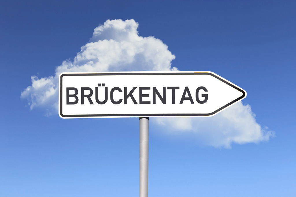 Brückentag Schild | (Fotomontage) Brückentag Symbolbild: Richtungspfeil mit der Aufschrift BRÜCKENTAG vor blauem Himmel - Realisiert mit Pictrs.com