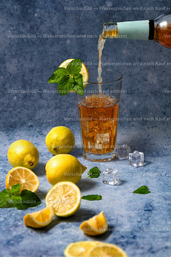 Eisgekühlter Zitronen Eistee wird in einen mit Minze und Zitronenscheibe dekorierten Glas eingschänkt | Eisgekühlter Zitronen Eistee wird in einen mit Minze und Zitronenscheibe dekorierten Glas eingschänkt. Im Vordegfrund sind teiweise angschnitteneund ganze Früchte zusammen mit Minze dekoriert. - Realisiert mit Pictrs.com