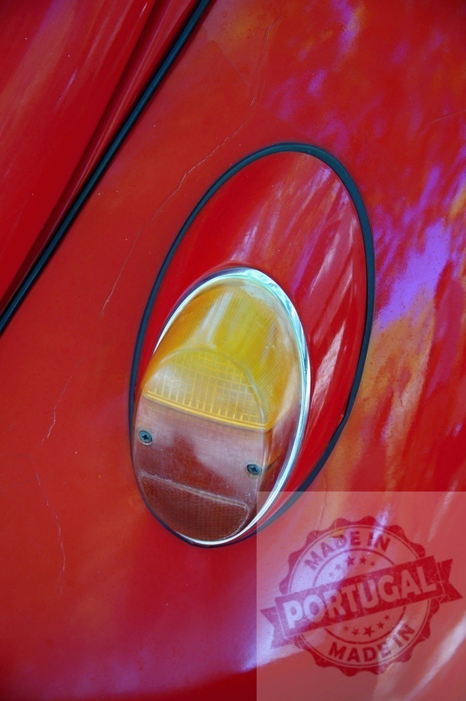 Close-up of a red Volkswagen Beetle taillight showing signs of age and wear | Oval taillight of a red vintage Volkswagen Beetle, highlighting its classic design and aged condition - Realized with Pictrs.com