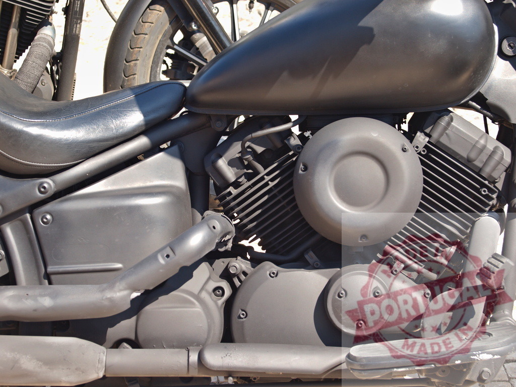 Matte black motorcycle engine with fuel tank details | Showing detailed view of a cruiser motorcycle's engine, fuel tank, and seat on a sunny day - Realized with Pictrs.com