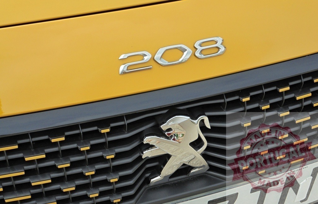 Peugeot 208 car chrome logo and grille on yellow hood | Peugeot 208 automobile featuring its chrome lion emblem and 208 lettering on a yellow car body - Realized with Pictrs.com