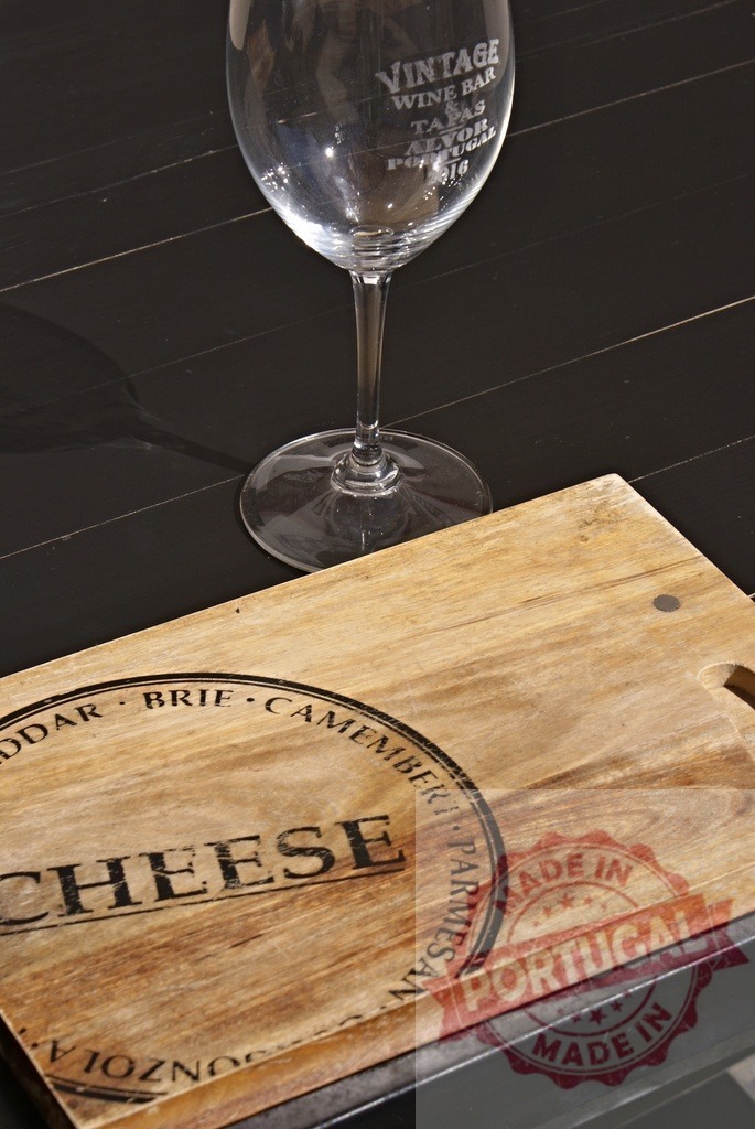 Vintage wine glass and wooden cheese board set | Vintage wine glass standing on a dark table next to a wooden cheese board - Realized with Pictrs.com