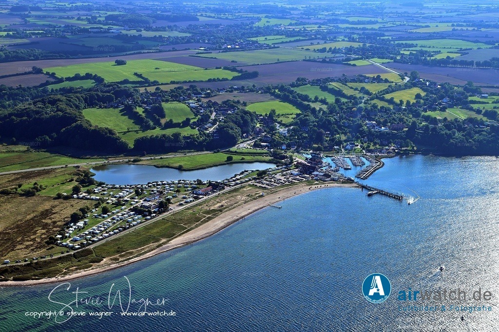 Luftbild Langballigau - Der Ort verfügt über einen Naturstrand mit Strandkorbverleih | Der Ort verfügt über einen Naturstrand mit Strandkorbverleih und einem offiziellen Hundestrand. Entlang der Strandpromenade finden sich Restaurants, Eisdielen und Imbissstände. Ein 2 km langer Weg verbindet den Hafen mit dem Ortszentrum von Langballig, einem anerkannten Luftkurort.