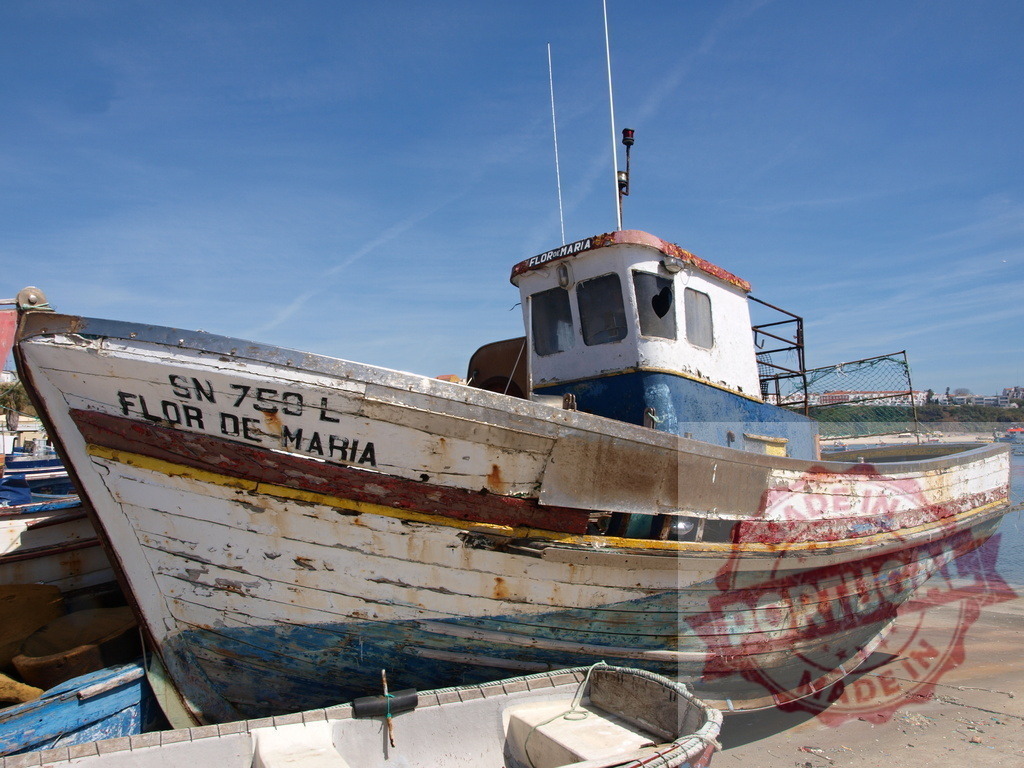 Flor de Maria fishing boat beached in Portugal harbor | Weathered wooden fishing boat resting on dry land under a clear blue sky - Realized with Pictrs.com