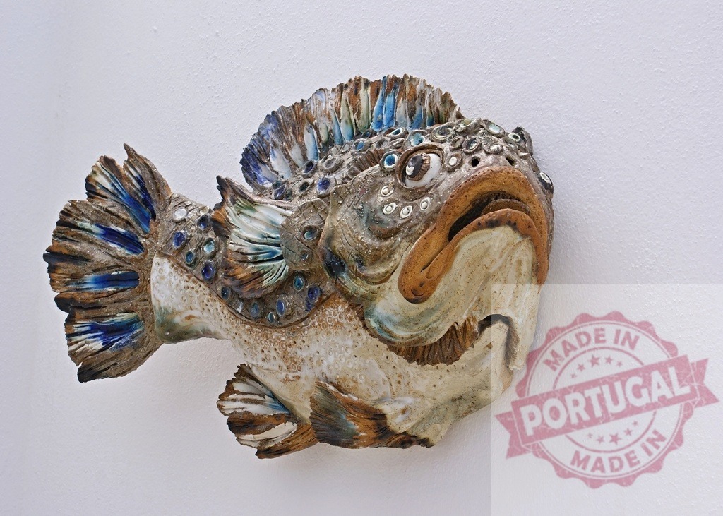 Ceramic fish art wall sculpture on white background | Ceramic fish sculpture with textured details and blue accents hanging on a white wall - Realized with Pictrs.com