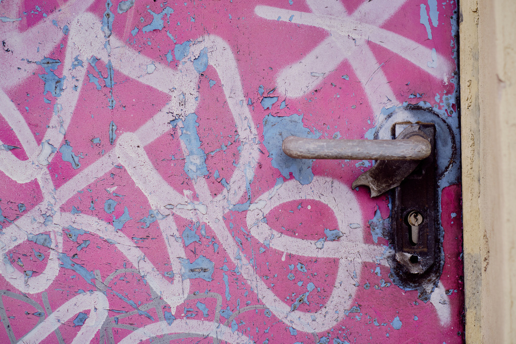 Alte rosarote Türe mit Griff und Graffiti | Wien, Austria - March 18, 2021: entlang der Wiener Gürtel Straße; Alte rosarote Türe mit Griff und Graffiti. - Realisiert mit Pictrs.com