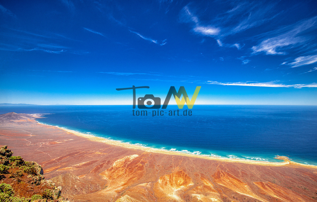 Blick vom Pico de la Zarza-Panorama Gipfelblick auf Cofete | Der Pico de la Zarza ist mit 807m die höchste Erhebung auf Fuerteventura. Vorausetzung vor einen tollen Ausblick ist auch eine wolkenfreie Wetterbedingung. Auch ist es gut - allerdings sehr selten - wenn es windstill ist. Durch die Böen wird viel Staub und Dreck aufgewirbelt. Hier der Ausblick auf den berühmten Cofete Strand. Die Villa Winter ist nicht sichtbar hinter dem Felsstück verborgen. - Realisiert mit Pictrs.com