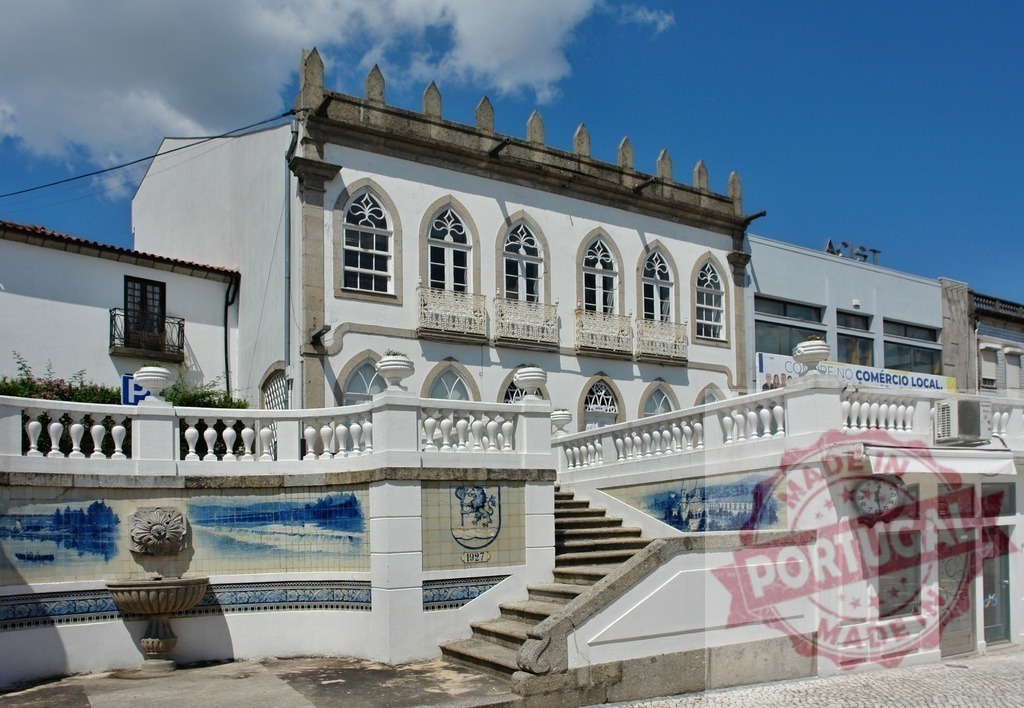 Portuguese neogothic building featuring azulejo tiles and fountain. Region Norte - Portugal | White architectural facade with pointed arch windows, decorative balustrade, and traditional blue azulejo tiles - Realisiert mit Pictrs.com