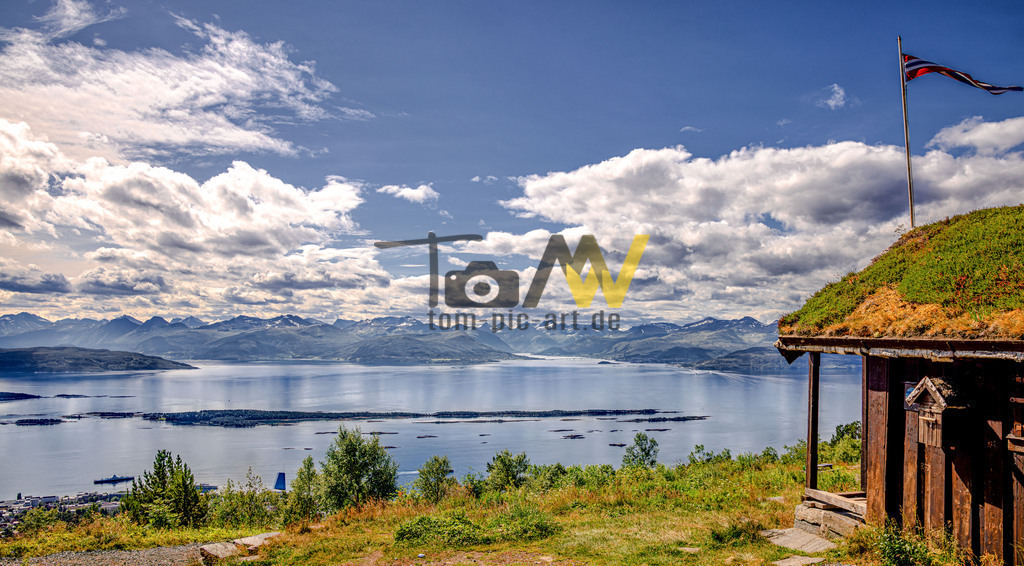 Toller Blick vom Gipfel des Varden-Molde-Norwegen-Fernblick | Das Bild zeigt den berühmten Ausblick vom Berg Varden auf die norwegische Stadt Molde, den Romsdalsfjord und das beeindruckende Panorama der Sunnmøre-Alpen. Der Aussichtspunkt Varden liegt 407 Meter über dem Meer. Das Panorama umfasst 222 teilweise schneebedeckte Berggipfel, von denen die meisten über 1000 Meter hoch sind. Molde, auch als „Stadt der Rosen“ bekannt, ist das Verwaltungszentrum der Provinz Møre og Romsdal in Westnorwegen. Die Stadt liegt an der Mündung des Romsdalsfjords und zieht seit über einem Jahrhundert Touristen an. In der Hütte auf der rechten Seite weht die norwegische Flagge. - Realisiert mit Pictrs.com