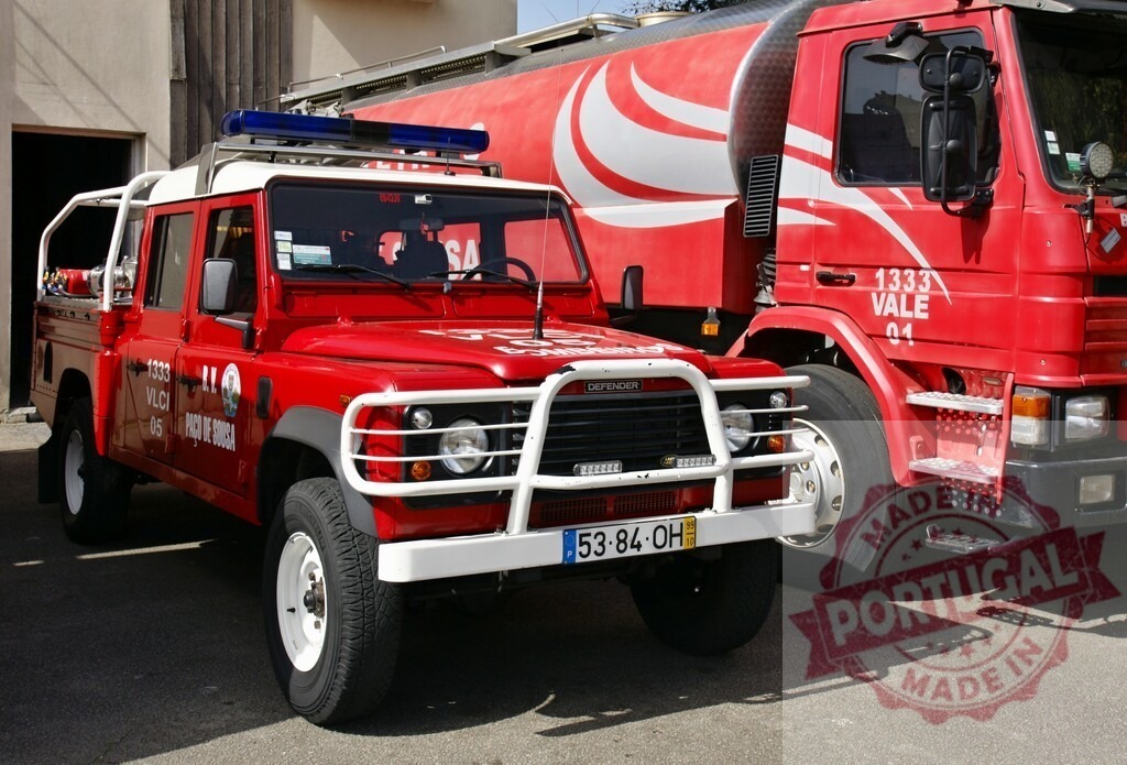 Land Rover Defender fire vehicle and fire truck | Red Land Rover Defender emergency vehicle parked beside a large fire engine at station - Realized with Pictrs.com