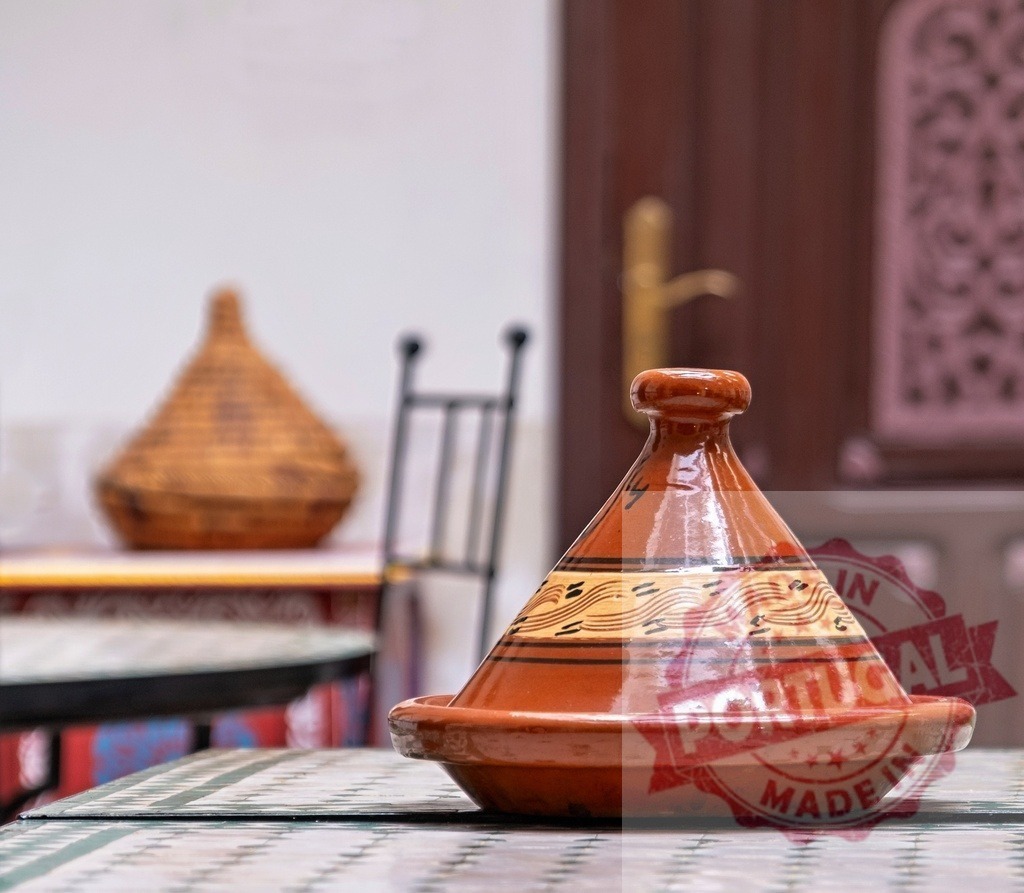 Traditional Moroccan Tajine resting on a table in Marrakech | Clay tajine placed on a mosaic table, ready to be used for cooking traditional Moroccan dishes - Realized with Pictrs.com