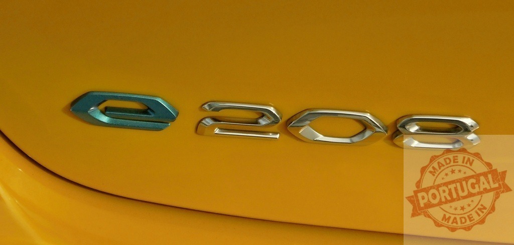 Peugeot e-208 electric vehicle badge on yellow car | Close-up of e-208 electric vehicle model name on yellow car body - Realisiert mit Pictrs.com
