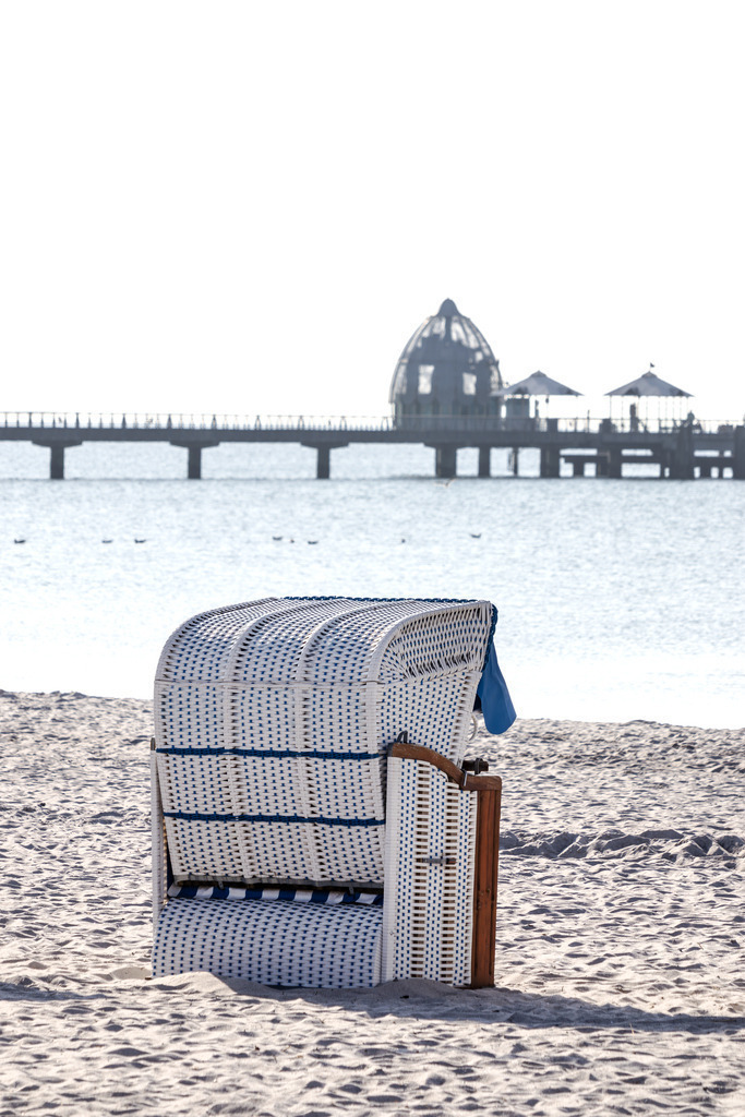 Wandbild: Ruhe am Meer – Grömitzer Strandmoment | Dieses maritime Wandbild zeigt einen ruhigen Moment am Strand von Grömitz. Im Vordergrund steht ein einzelner Strandkorb auf hellem Sand – bereit für entspannte Stunden mit Blick aufs Meer. In der Ferne erkennt man die Seebrücke von Grömitz, die sich elegant ins Wasser erstreckt und mit ihrer markanten Tauchglocke einen besonderen Akzent setzt. Das Wasser liegt ruhig, und der Himmel ist klar und freundlich. Die Komposition vermittelt Gelassenheit und lädt zum gedanklichen Abschalten ein. Dieses Motiv bringt die stille Schönheit der Ostsee direkt an die Wand und eignet sich ideal für maritime Wohnkonzepte. Erhältlich als Leinwandbild, Acrylglasbild, Alu-Dibond FineArt Print oder als Akustikbild – ein stilvoller Blickfang für Zuhause, Büro oder Ferienwohnung. - Realisiert mit Pictrs.com