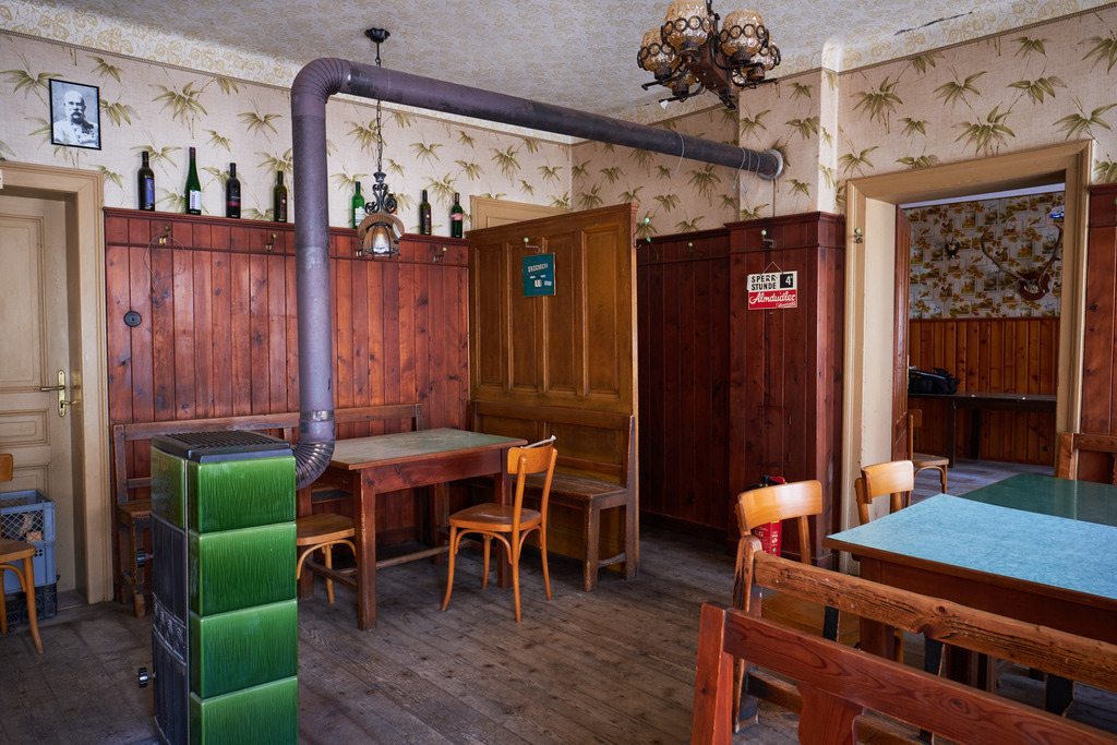 Innenraum einer leeren Gaststätte im Weinviertel | Austria - June 08, 2021: Innenraum einer leeren Gaststätte im Weinviertel; Blick in die Gaststube mit Holzofen. - Realisiert mit Pictrs.com
