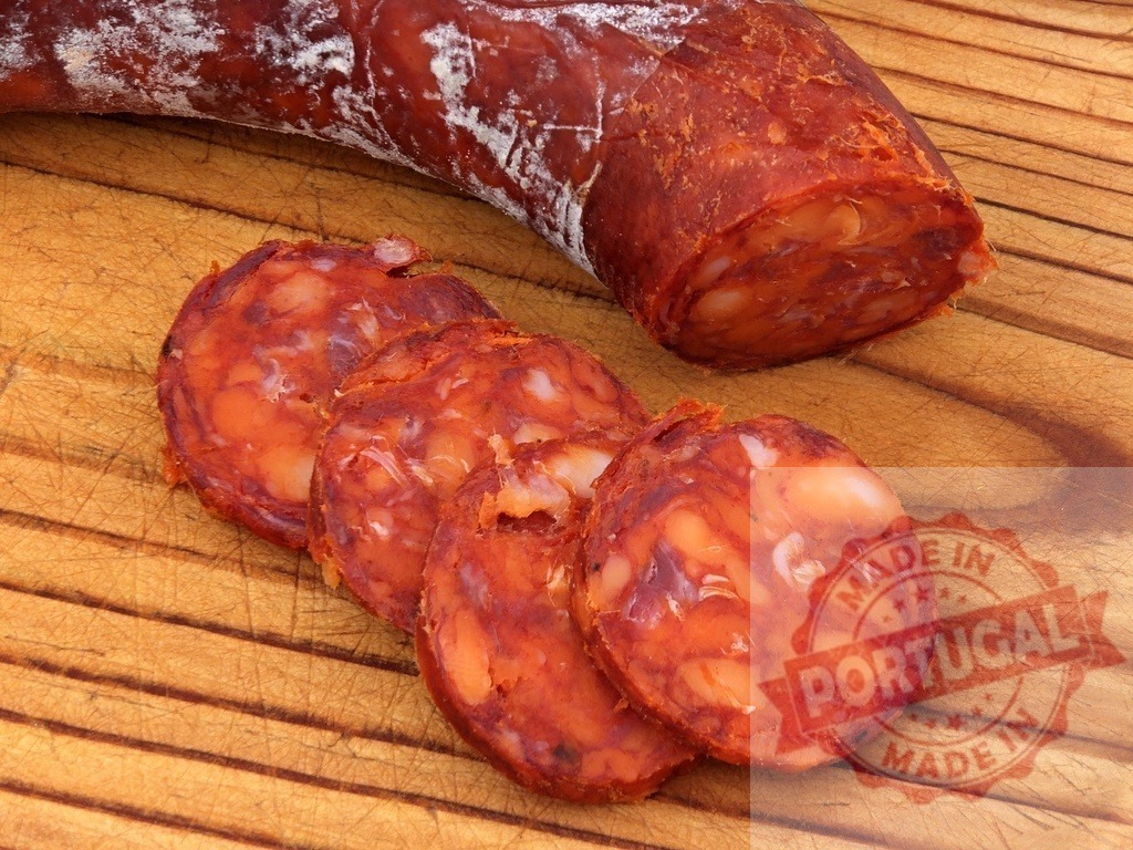 Chorizo sausage slices on wooden background | Spicy Spanish chorizo sausage cut into slices, ready for snacking or appetizer - Realized with Pictrs.com