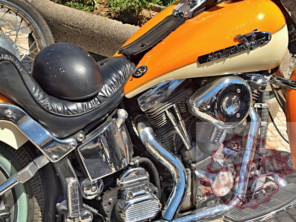 Harley-Davidson motorcycle with black helmet on seat | Orange and cream Harley-Davidson motorcycle showing chrome engine parts and a black helmet - Realisiert mit Pictrs.com