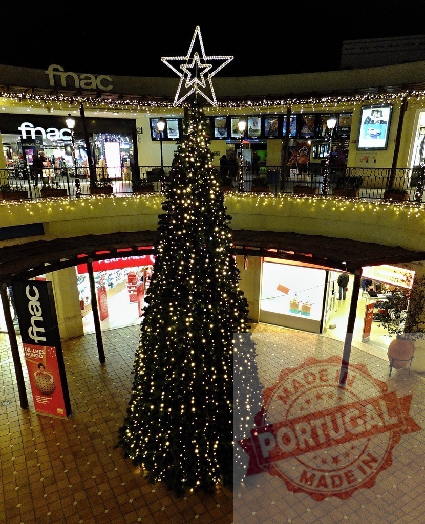 Christmas tree illuminating shopping mall during holidays at night | Large decorated Christmas tree standing in the center of a shopping mall, bringing festive cheer to holiday shoppers - Realized with Pictrs.com
