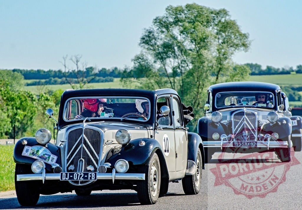 Citroën Traction Avant rally cars driving on sunny road | Two vintage Citroën Traction Avant cars participating in a classic car rally on a rural road - Realized with Pictrs.com