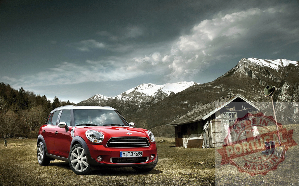 Shiny red Mini Countryman parked in the mountains near a wooden hut | Brand new Mini Countryman parked near a mountain hut with snowy peaks in the background - Realisiert mit Pictrs.com