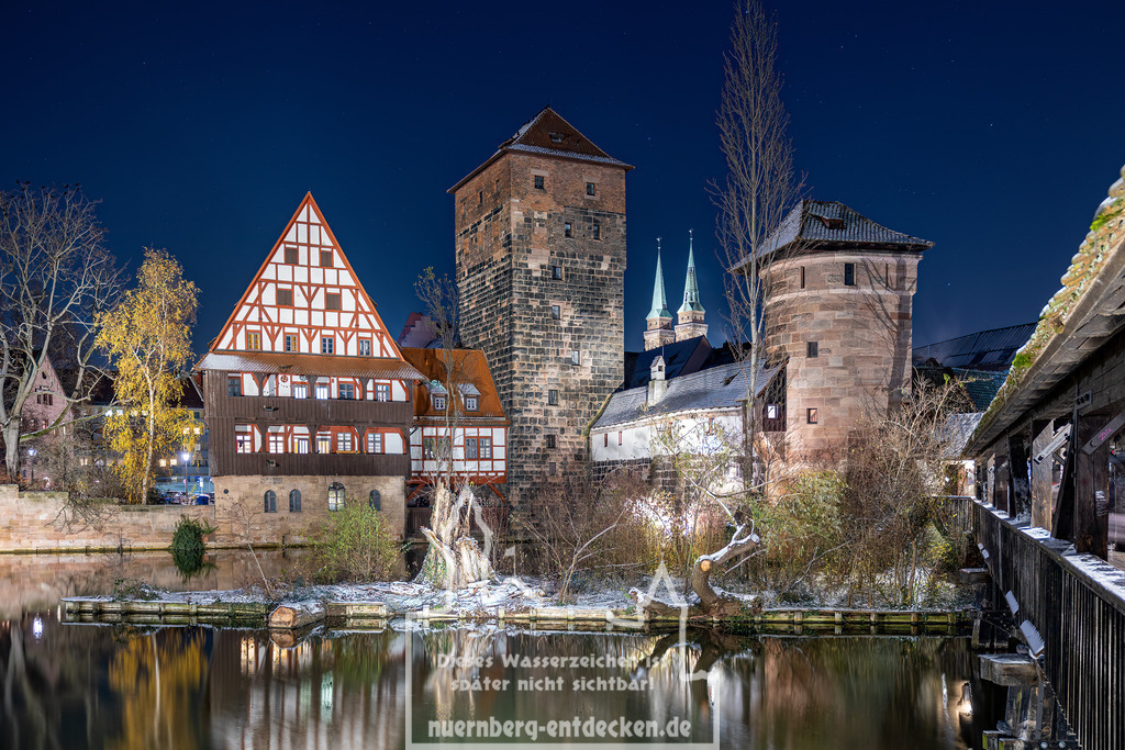Monatsbild des Kalender 2025 für den Monat Dezember | Weinstadel mit angrenzenden Wasserturm in der Altstadt von Nürnberg bei Nacht im Winter. Im Hintergrund sind die Türme von der Kirche in St. Sebald zu sehen. - Realisiert mit Pictrs.com