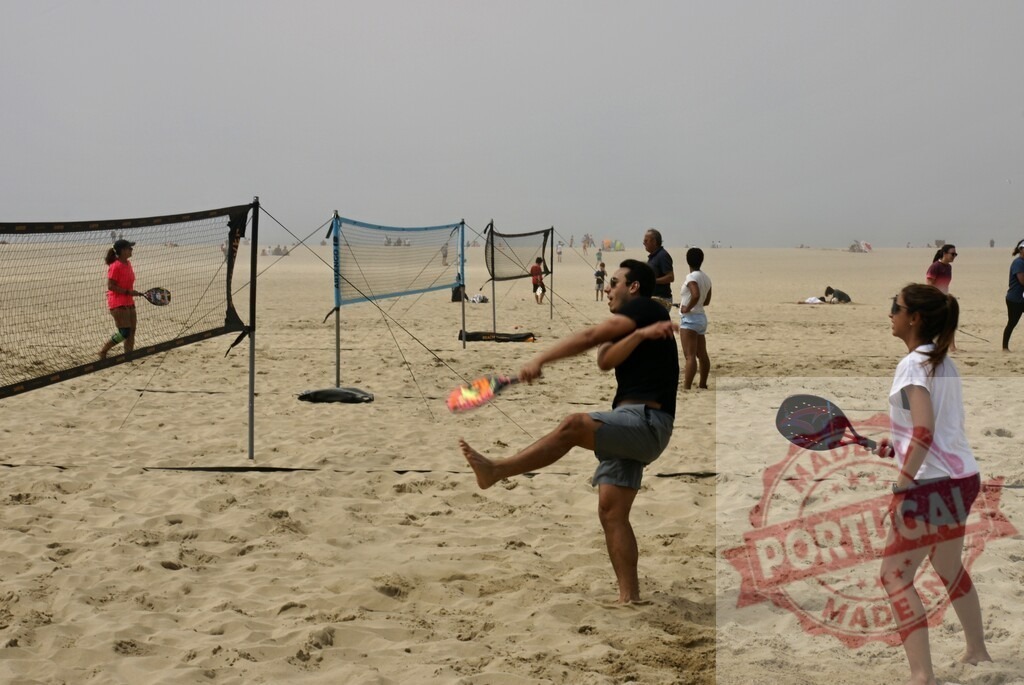 People playing beach tennis on sandy beach | Young adults enjoying beach tennis game on a crowded sand beach during summer - Realized with Pictrs.com