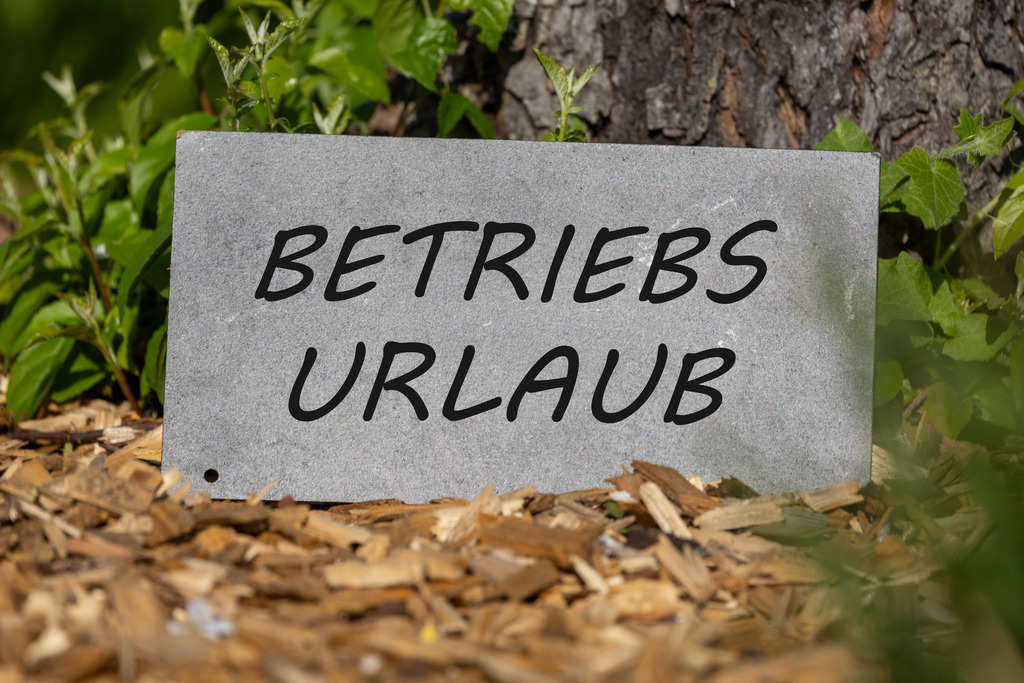 Schild im Garten mit (hinzugefügtem) Text BETRIEBSURLAUB | Schild im Garten mit (hinzugefügtem) Text BETRIEBSURLAUB - Realisiert mit Pictrs.com
