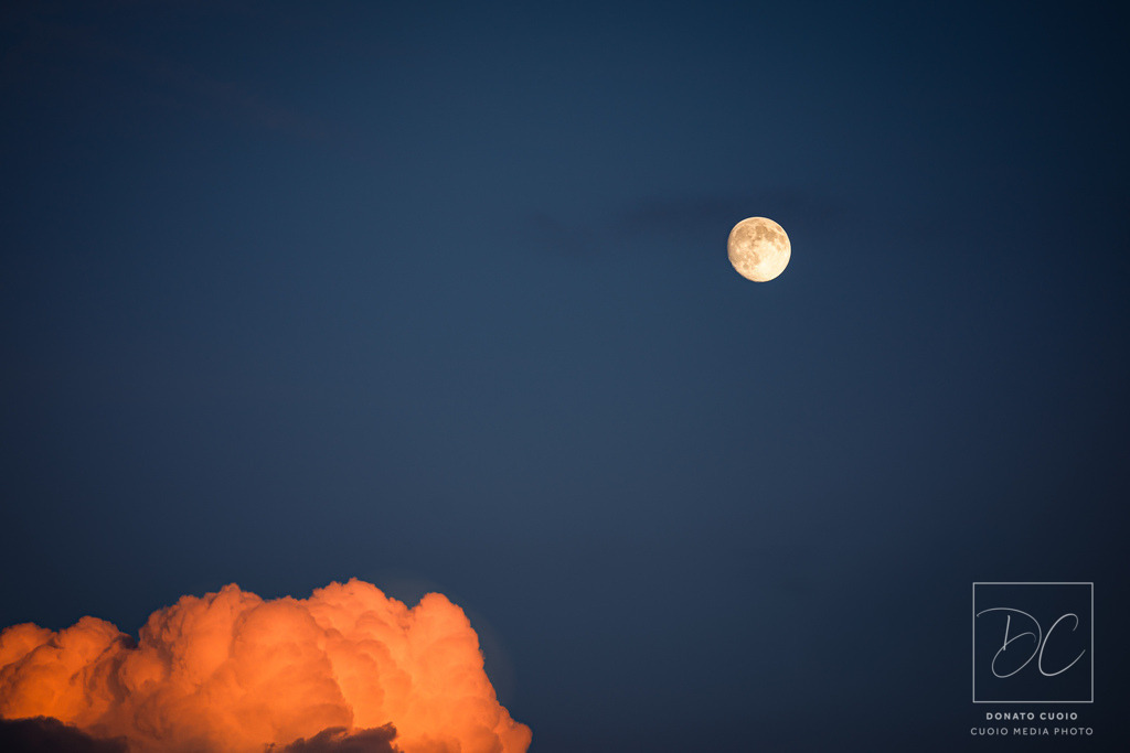 Stille Dualität – Der leuchtende Atem der Nacht | Ein Moment der vollkommenen Ruhe – eingefangen zwischen Tag und Nacht. Die Fine-Art-Fotografie „Stille Dualität“ zeigt eine leuchtend orangefarbene Wolkenformation im Kontrast zu einem klaren Vollmond in der blauen Dämmerung. Diese außergewöhnliche Komposition verbindet minimalistisches Design mit emotionaler Tiefe.Ob im Wohnzimmer, im Büro oder in meditativen Räumen: Dieses Bild verleiht jeder Umgebung eine beruhigende, inspirierende Atmosphäre. - Realisiert mit Pictrs.com