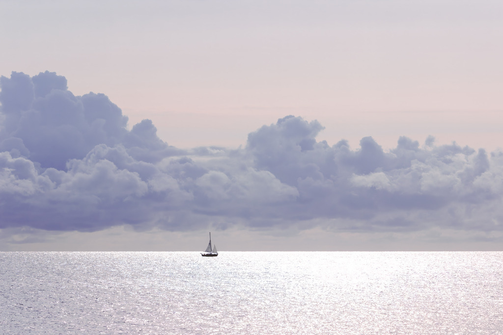 Allein auf dem Meer – Segelboot in morgendlicher Lichtstimmung | Dieses Motiv zeigt ein einzelnes Segelboot, das ruhig über die weite Wasserfläche gleitet. Die morgendliche Lichtstimmung legt einen sanften Glanz auf das Meer und lässt die Wolken weich und leicht erscheinen. Der klare Horizont und die stille See betonen die Einsamkeit und Freiheit des Segelns. Die Komposition vermittelt Ruhe, Weite und einen Moment der vollkommenen Gelassenheit. Als Wandbild erhältlich auf Acrylglas und weiteren hochwertigen Materialien.