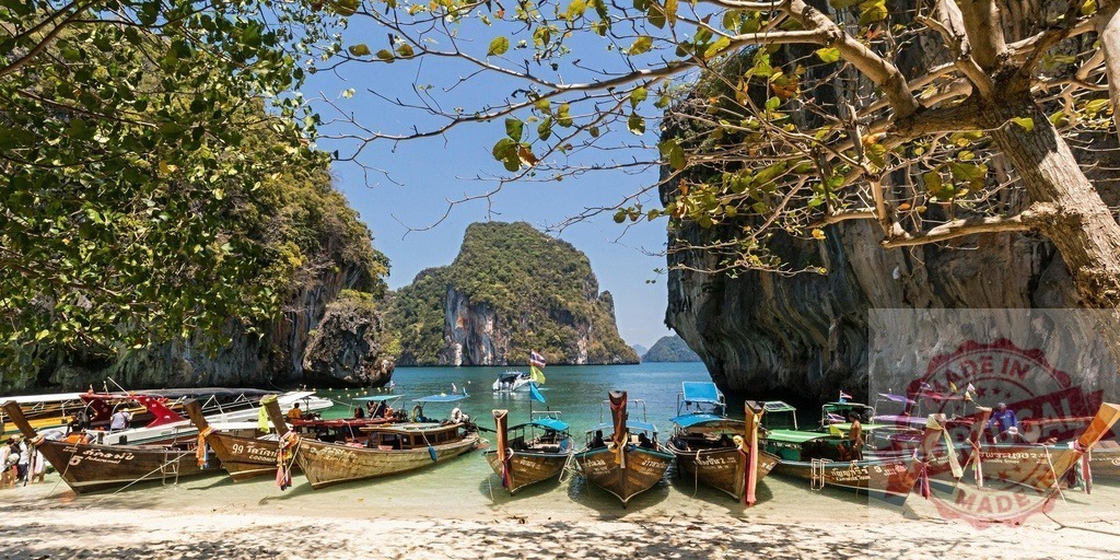 Traditional longtail boats resting on a tropical beach in Thailand | Colorful longtail boats moored on a beautiful beach in Thailand, surrounded by lush vegetation and stunning rock formations - Realisiert mit Pictrs.com