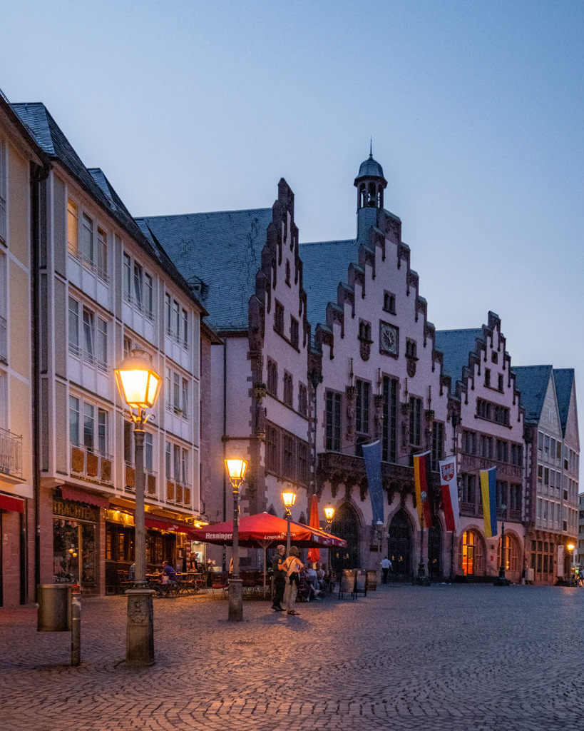 Römerberg in Frankfurt zur blauen Stunde | Die historischen Fachwerkhäuser am Frankfurter Römerberg leuchten am Abend über dem gepflasterten Platz. Das warme Licht der Fassaden trifft auf die kühle Stimmung der blauen Stunde. - Realisiert mit Pictrs.com
