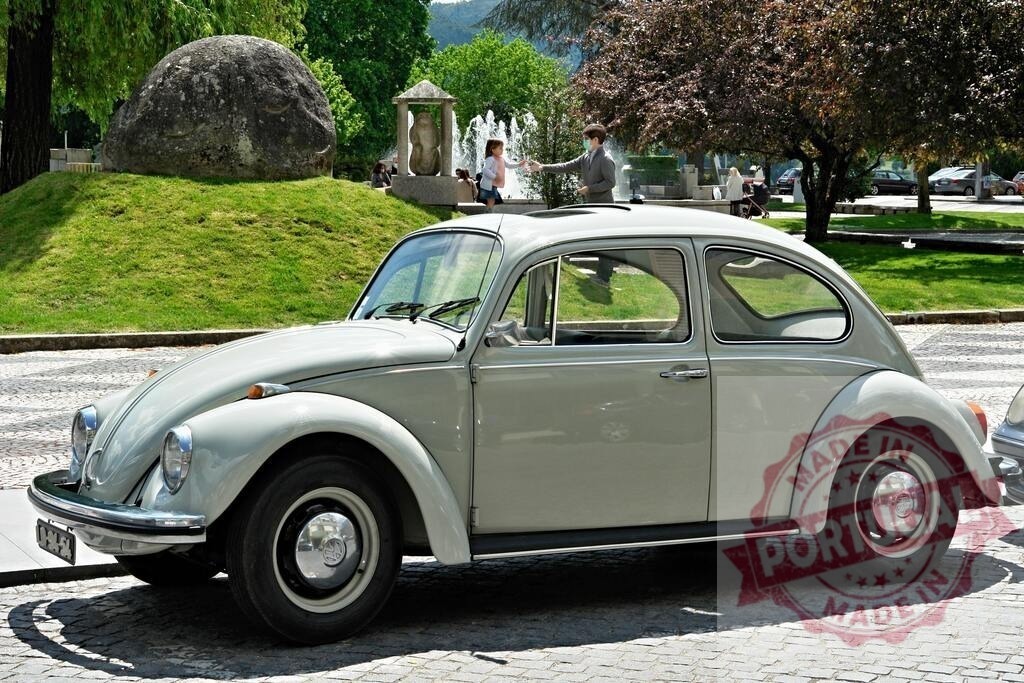 Classic Volkswagen Beetle parked near a fountain with people interacting in the background | Vintage Volkswagen Beetle car parked on a cobblestone street, with a fountain and people interacting in the background, evoking a nostalgic atmosphere - Realized with Pictrs.com