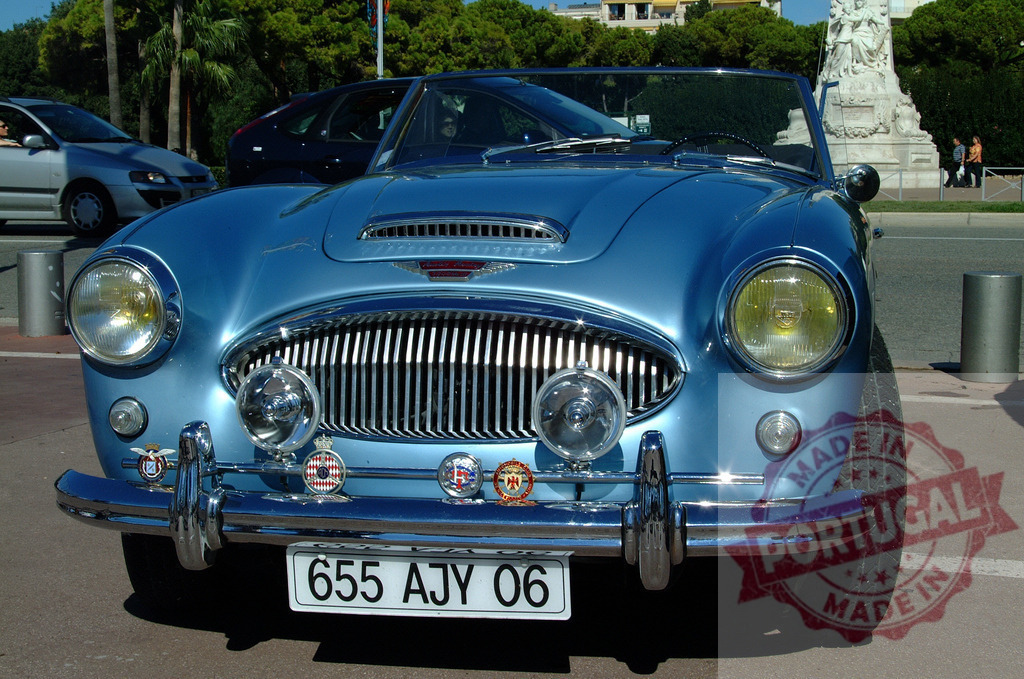 Light blue Austin-Healey 3000 parked in a street | Classic light blue Austin-Healey 3000 with several badges on the bumper, parked in a street - Realisiert mit Pictrs.com