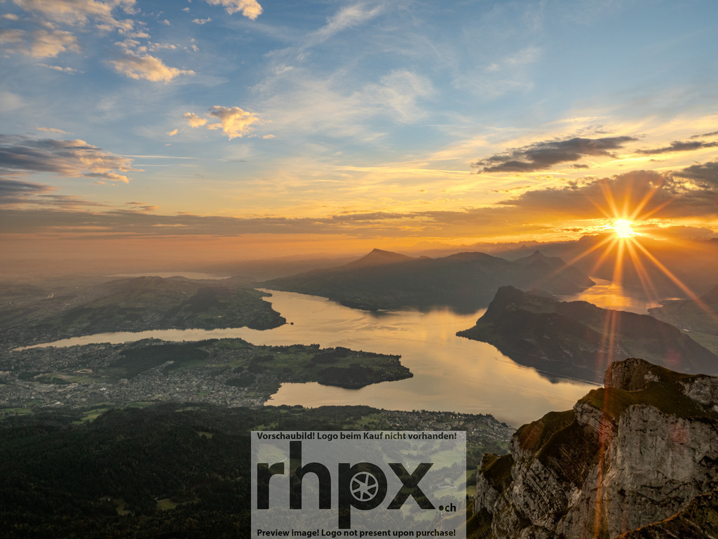 Sonnenstern über dem Vierwaldstättersee | Licht. Weite. Erwachen.Ein spektakulärer Sonnenstern durchbricht den Horizont und taucht die Zentralschweizer Alpen in goldenes Licht. Dieser magische Moment auf dem Pilatus fängt die erhabene Ruhe des erwachenden Tages über dem See perfekt ein.Wähle unter "Produktauswahl" dein Wunschformat: Vom klassischen Wandbild über Puzzle &amp; Tassen bis zum digitalen Download (z.B. als Handy-Hintergrund). - Realisiert mit Pictrs.com