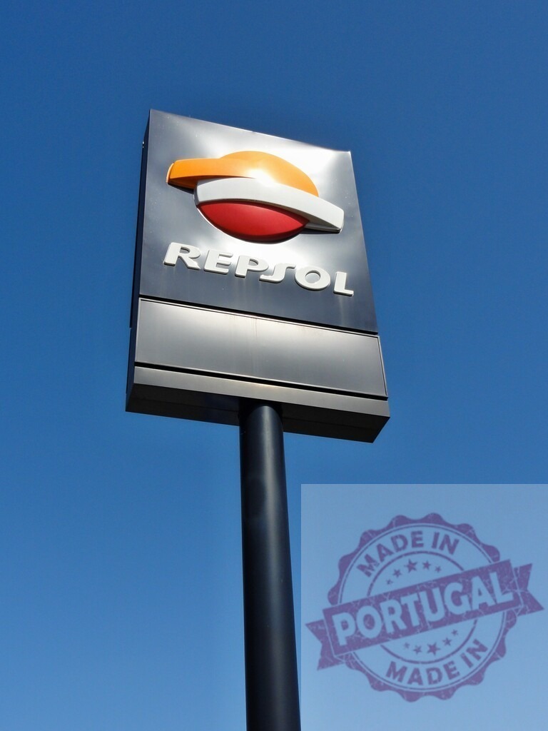 Repsol logo sign against a clear blue sky | Repsol logo displayed on a tall corporate sign at a gas station - Realisiert mit Pictrs.com