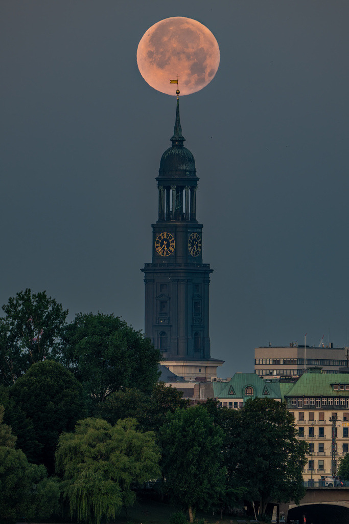 Vollmond über dem Hamburger Michel | Der Vollmond steht über dem Turm der Hauptkirche St. Michaelis und bildet gemeinsam mit der Hamburger Stadtsilhouette ein markantes Morgenmotiv. - Realisiert mit Pictrs.com
