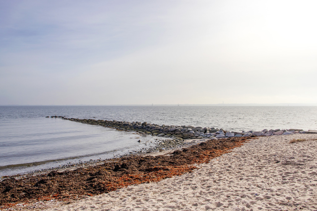 Wandbild: Sandstrand in Strande an der Kieler Förde | Dieses Wandbild im Querformat zeigt den Sandstrand in Strande in schöner Lichtstimmung. Am Himmel sind viele Schleierwolken zu sehen. - Realisiert mit Pictrs.com