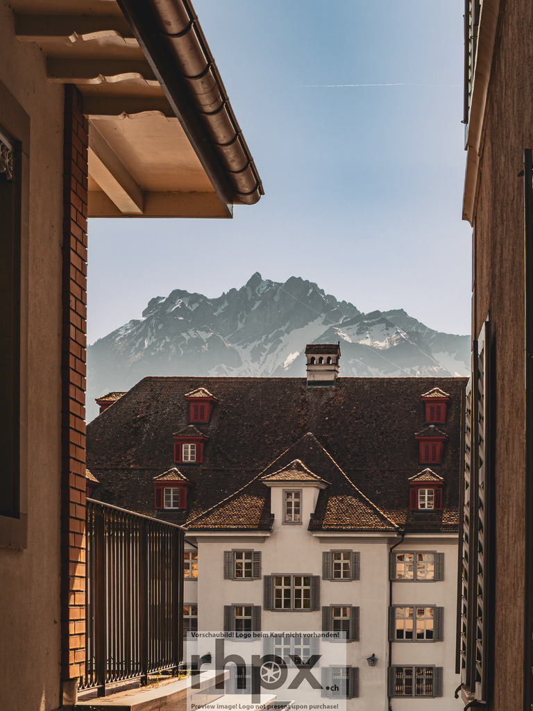 Luzern Altstadt mit Pilatus – Blick durch Gasse | Blick durch eine enge Gasse der Luzerner Altstadt auf ein historisches Gebäude mit dem Pilatus im Hintergrund.  - Realisiert mit Pictrs.com