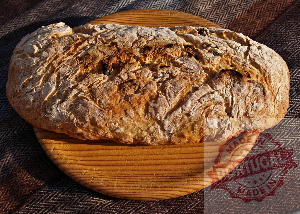 Homemade rustic bread loaf baking fresh on a wooden board | Rustic homemade crusty loaf of bread sitting on a wooden cutting board - Realized with Pictrs.com
