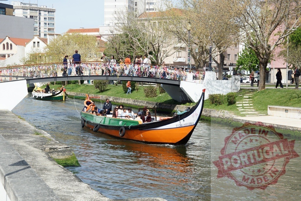 Traditional moliceiro boat navigating Aveiro canal in Portugal. Aveiro - Portugal | People enjoying a traditional moliceiro boat tour along the canal in Aveiro - Realisiert mit Pictrs.com