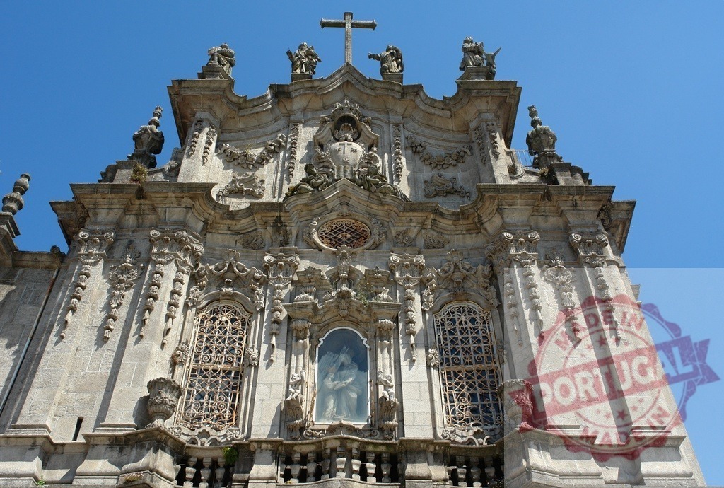 Clerigos church ornate baroque facade against clear sky | Ornate baroque facade of Clerigos church with statues, cross and blue sky in Porto, Portugal - Realized with Pictrs.com